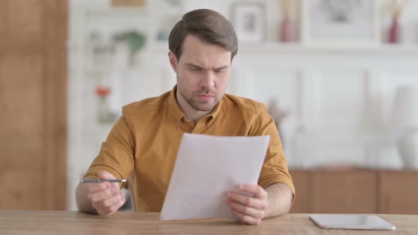 Young Man Reacting to Loss on Documents in Office