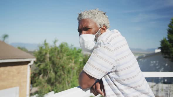 Senior man wearing face mask standing in the balcony