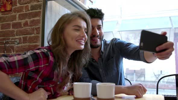 Video calling. Happy couple using phone for video call in cafe