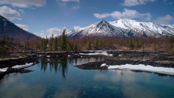 Flying Over Lakes with Floating Ice with Snowcapped Mountains Around