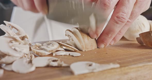 Close up of a chef knife slicing champignon mushrooms