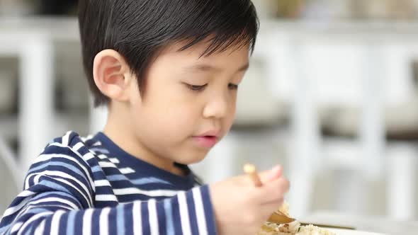 Cute Asian Child Eating Breakfast In A Restaurant 