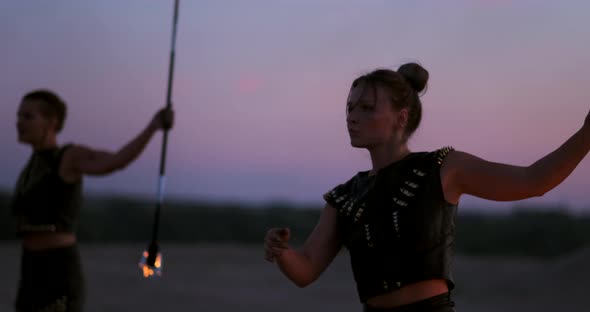 Women with Fire at Sunset on the Sand Dance and Show Tricks Against the Beautiful Sky in Slow Motion