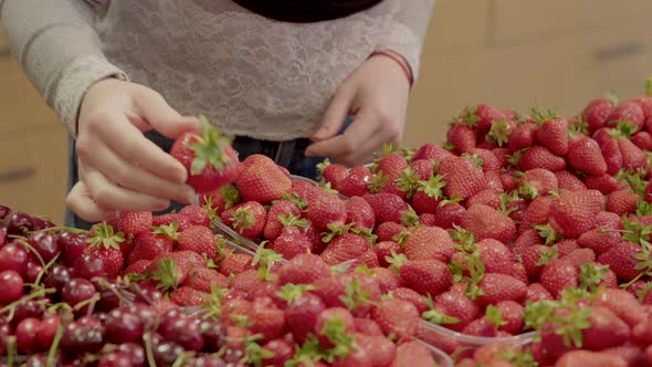 Unrecognizable Young Caucasian Woman Choosing Sweet Strawberry in Supermarket. Close-up of Female