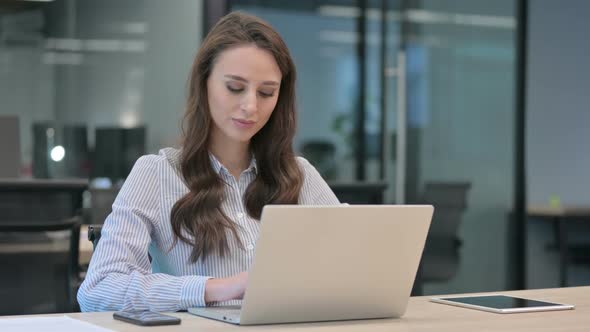 Young Businesswoman Smiling at Camera while working on Laptop