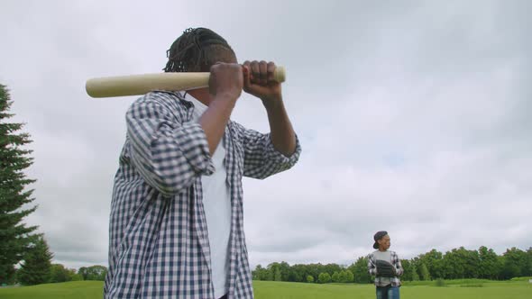 Closeup of African Dad with Baseball Bat Batting Son's Pitch on Field