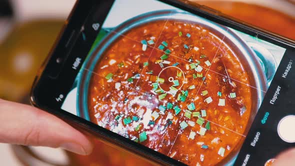 Female Hands Taking a Picture on a Smartphone Traditional Ukrainian Red Borscht