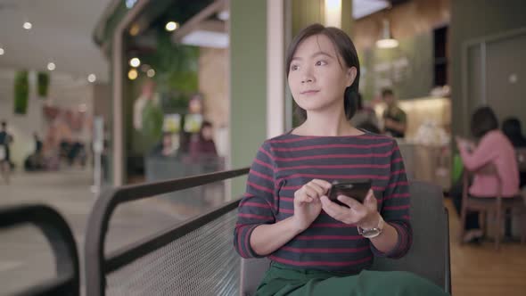 Happy asian woman using smartphone in cafe
