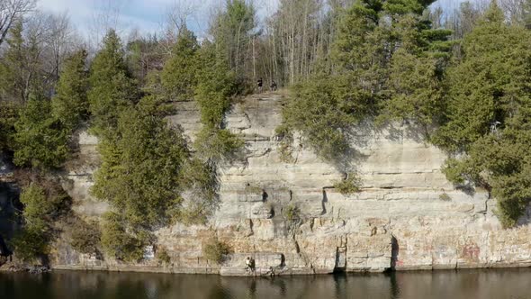 Girl Rock Climber Rappelling and Rock Climbing a Steep Cliff Wall of a Lake
