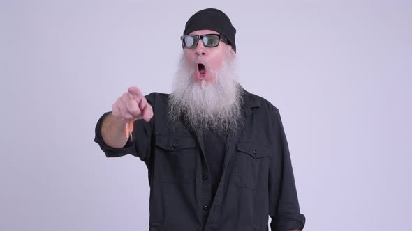 Mature Bearded Hipster Man Looking Surprised and Pointing Finger