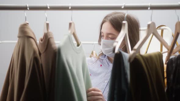 Woman with Covid Mask Shopping for Dress in Clothing Retail Store or Fashion Showroom