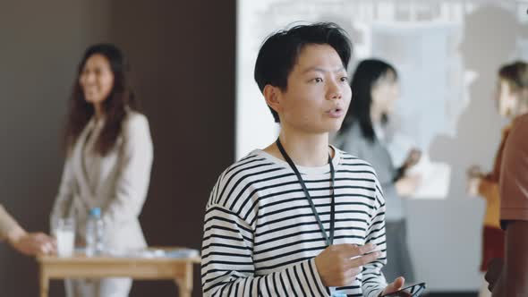 Asian Woman Having Talk with Colleague on Business Event