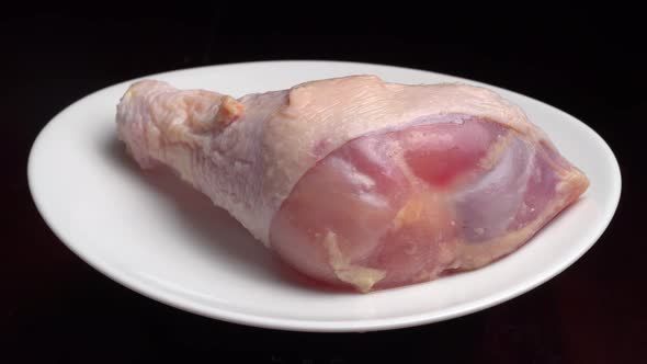 chicken leg or thigh with shin lies on white plate and rotates on turntable