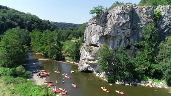 4K Aerial view of people jumping into the water from high rock