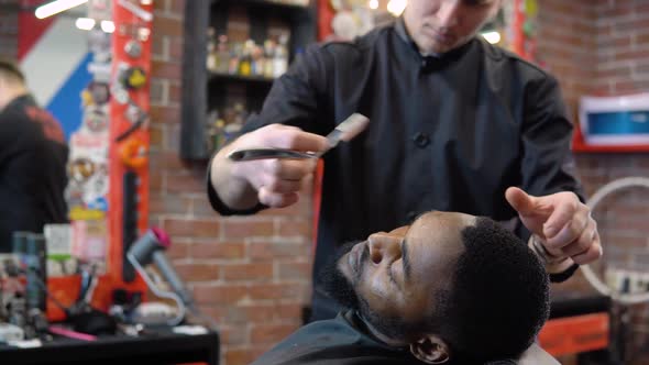 The Hairdresser Cuts the Client's Beard with a Clipper