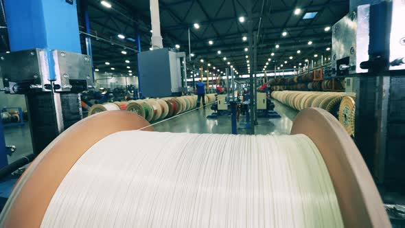 White Cable Unwinding From a Large Spool at a Factory