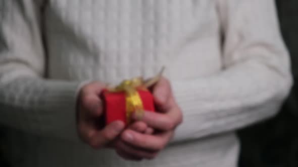 closeup of a man's hands holding out a red gift box. gift giving concept. selective focus.