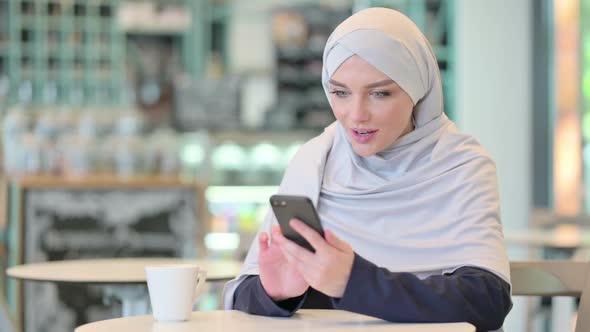 Excited Young Arab Woman Celebrating Success on Smartphone