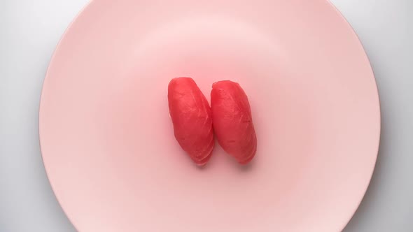 Top View of Spinning Two Tuna Nigiri Sushi on the Spinning Pink Plate.