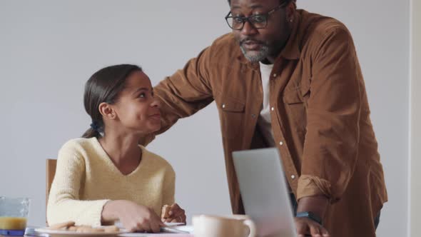 African daughter showing her father something in a notebook