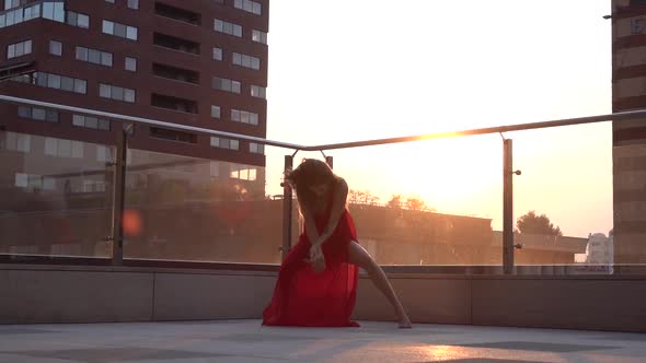 Beautiful Young Girl Dancing on the Street of a Modern City in the Sunset Light. She Is Wearing a