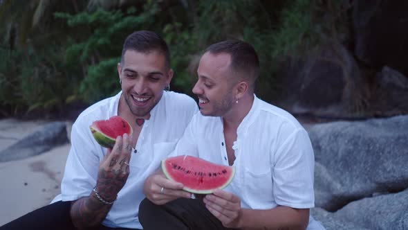 Two Male Young Gay Guys Enjoy Their Honeymoon Vacation on a Tropical Island Eating Watermelon on the