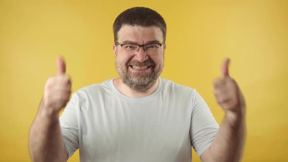 Caucasian middle-aged man in glasses with a beard showing thumbs