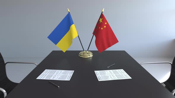 Flags of Ukraine and China and Papers on the Table