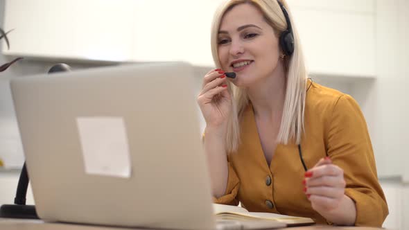 Woman in Headphones Communicates By Video Call on a Laptop