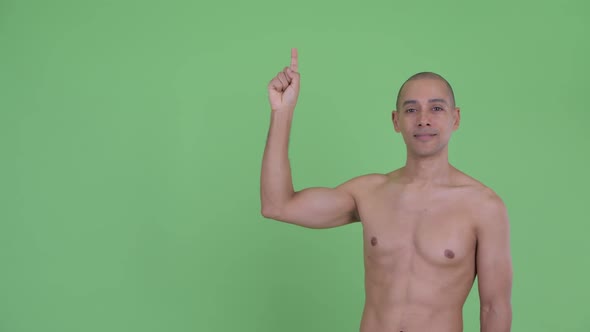 Happy Bald Multi Ethnic Shirtless Man Pointing Up and Giving Thumbs Up