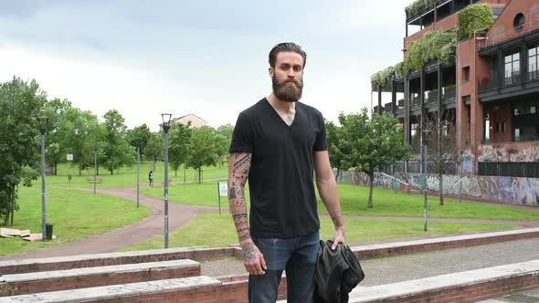 young beautiful bearded man posing outdoor looking camera