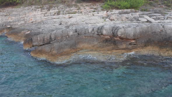 Close up shot of a rocky shore with waves splashing against it. Parallax camera shot over the water.