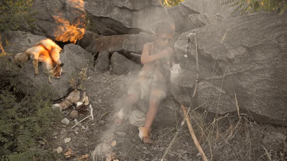 Caveman Manly Boy Making Primitive Stone Weapon in Camp