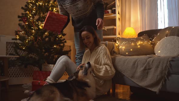 Family Celebrating Christmas with Cute Corgi Dog at Festive Decorated Cozy House