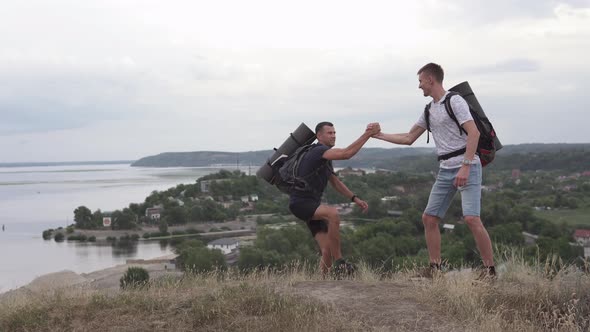 The athlete gives a helping hand to a friend on the mountainside.