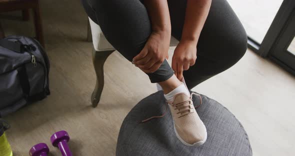 Video of legs of plus size african american woman in sport clothes tying shoes