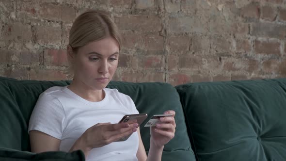 Close-up woman buys online shopping at home with credit card and phone. woman type entering 