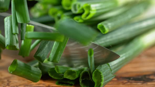 Super Slow Motion Shot of Cutting Spring Onion on Wooden Cutting Board at 1000Fps.