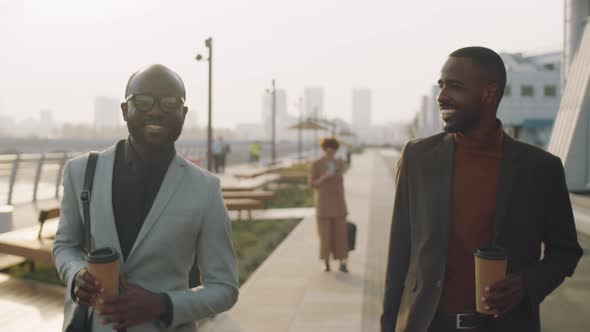 African American Businessmen Walking with Coffee Outdoors and Speaking