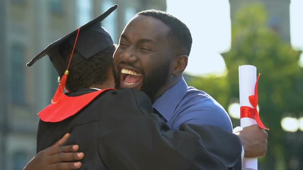 Black Father and Son Hugging in University Campus After Graduation Ceremony