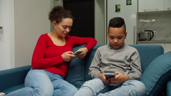 Mother and Her Preteen Son Using Smartphone Surfing the Net Indoors alt