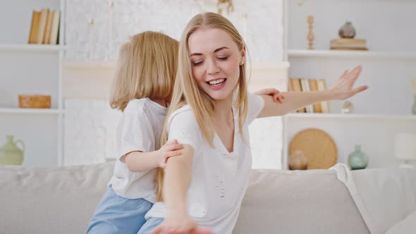 Young Caucasian Happy Mother Woman Babysitter Plays with Little Daughter Child Toddler Small Girl in