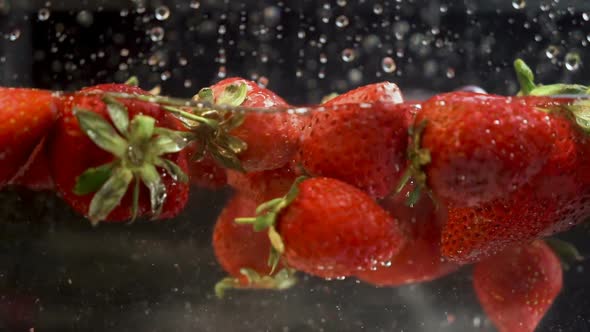 Vibrant strawberries falling and floating in aquarium full with water