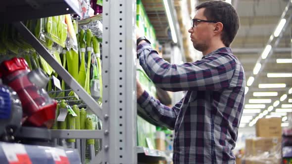 A Man in Glasses Selects Garden Tools for a Country Site in a Supermarket