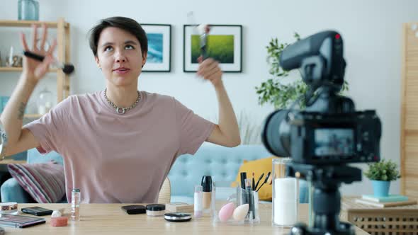 Cheerful Vlogger Recording Tutorial About Makeup Talking and Gesturing Using Camera at Home