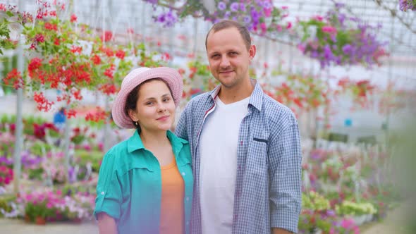 Family of Successful Flower Growers Stands in a Greenhouse Look at Each Other Look at Camera