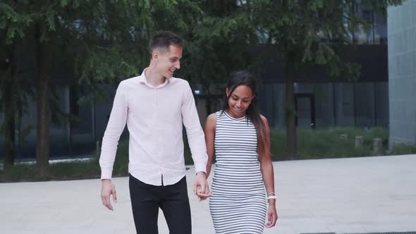 Two Multiracial Beloved Ones Walking Down the Street, Hugging and Talking To Each Other