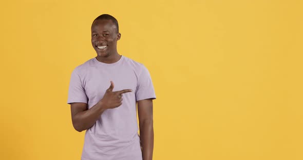 Cheerful Friendly Black Guy Showing Something, Pointing Away at Copy Space