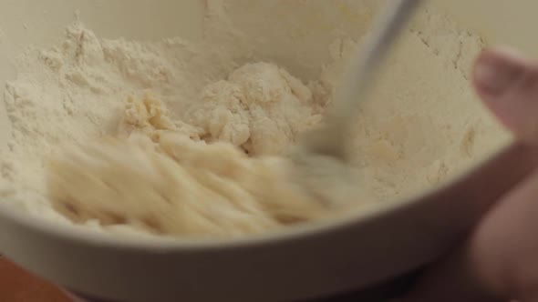 Hand mixing ingredients with flour in a bowl close up shot