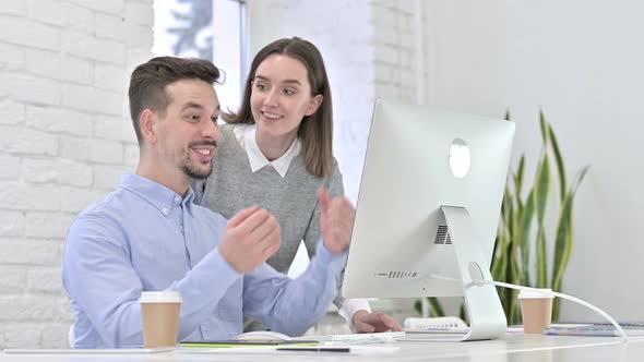 Creative Team Celebrating Success on Desktop By High-Five in Office